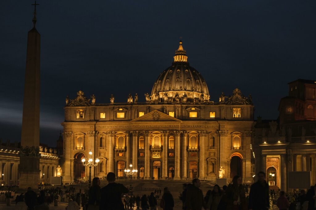 Photo by Olga Lioncat: https://www.pexels.com/photo/st-peters-basilica-facade-against-unrecognizable-citizen-silhouettes-at-night-7245252/
